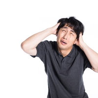 頭を抱えて焦る男性のストレスと悩みの表情の写真