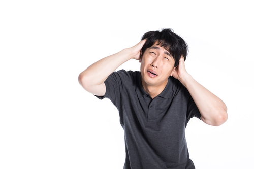 頭を抱えて焦る男性のストレスと悩みの表情