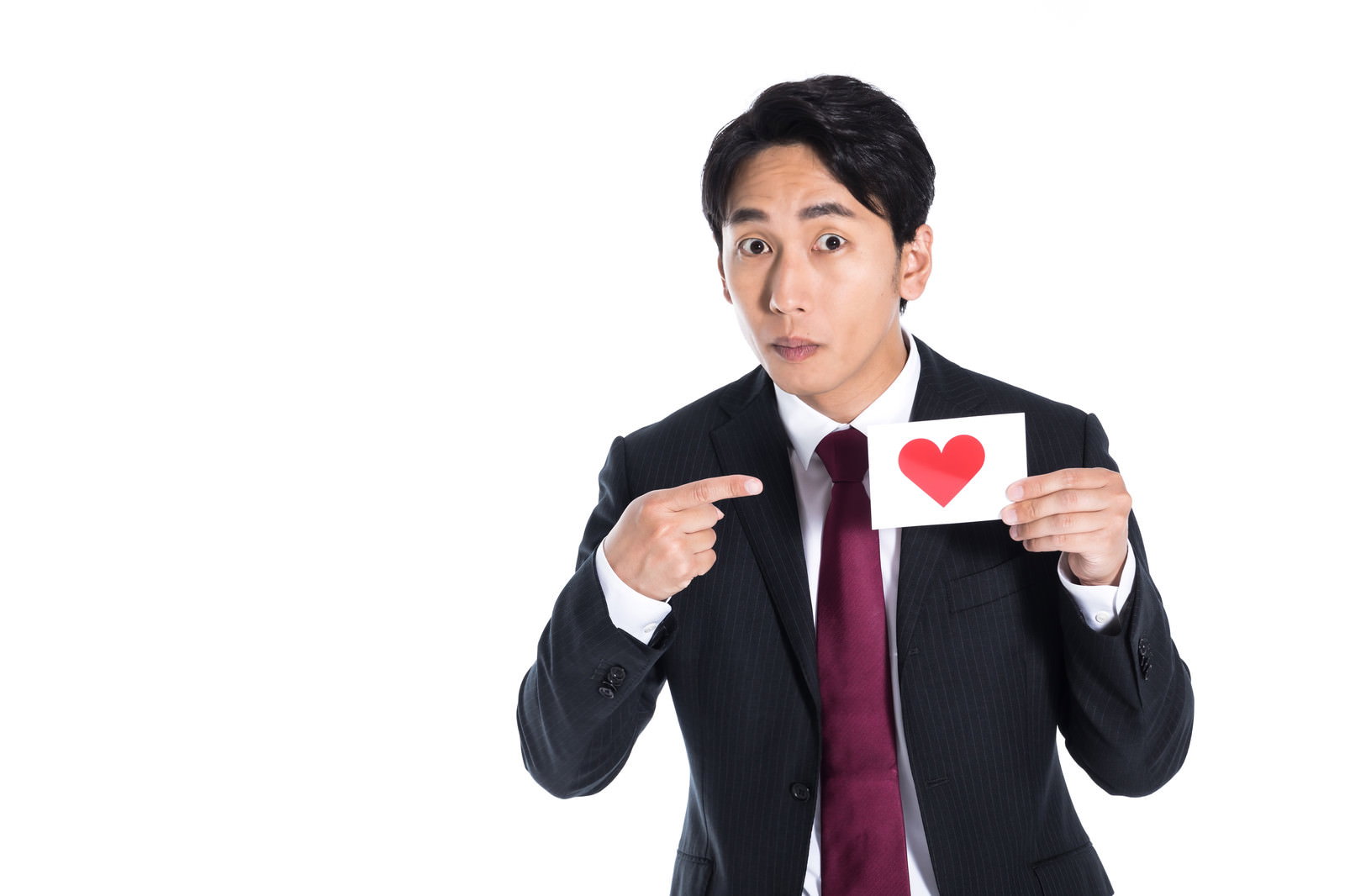 スーツ姿の男性がハートマークのカードを持ち指を差している［モデル：大川竜弥］