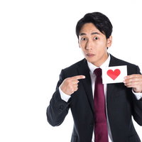 いいねを促すSNS担当の男性がハートマークを指すの写真