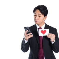 スマートフォンの心拍数ログにハート反応を示すスーツ姿の男性の写真