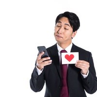 推しメンがリプライにいいねしてくれた瞬間を確認するスーツ姿の男性の写真