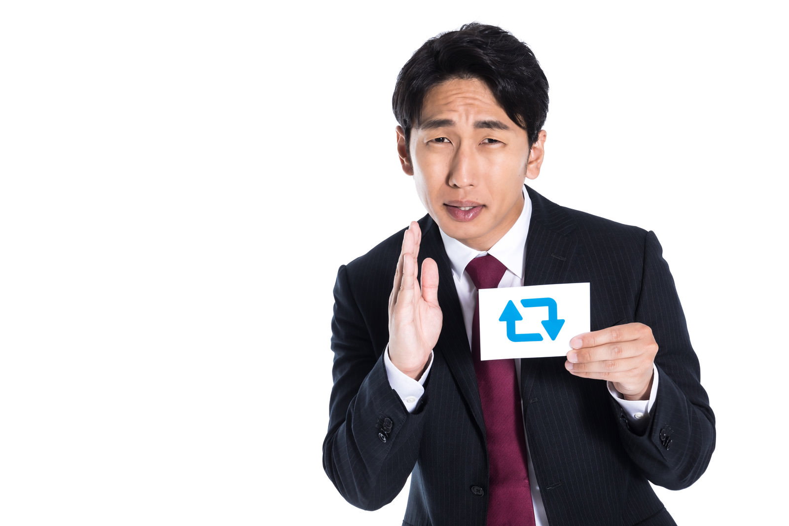 片手を上げてお願いするポーズでスマートフォンを持つスーツ姿の男性［モデル：大川竜弥］