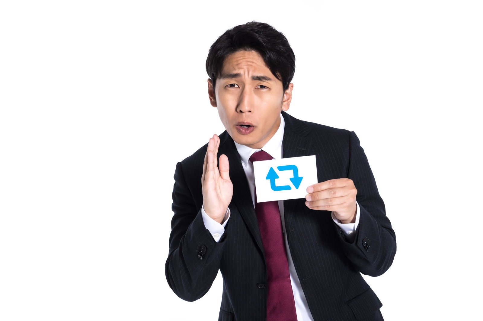 青い矢印アイコンのカードを持ち、拡散を促すジェスチャーをするスーツ姿の男性［モデル：大川竜弥］