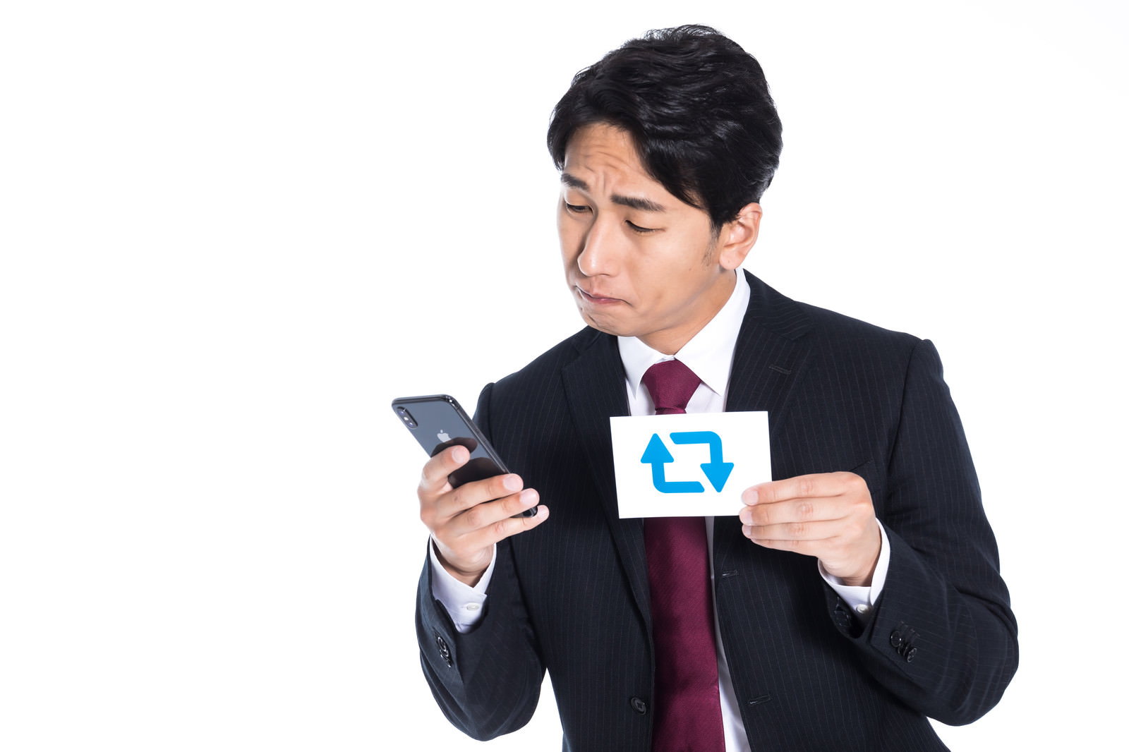 黒いスーツを着た男性がスマートフォンを見ながら名刺を持っている［モデル：大川竜弥］