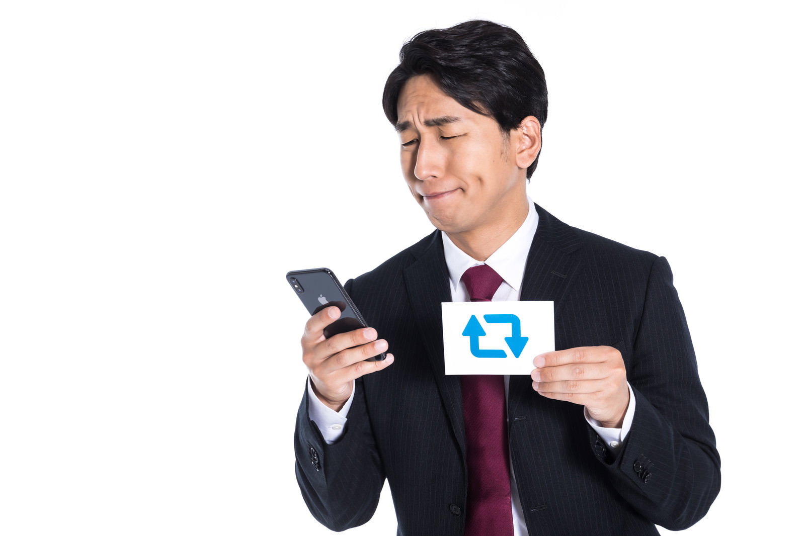 スマートフォンを見ながら名刺を持つ黒いスーツの男性［モデル：大川竜弥］