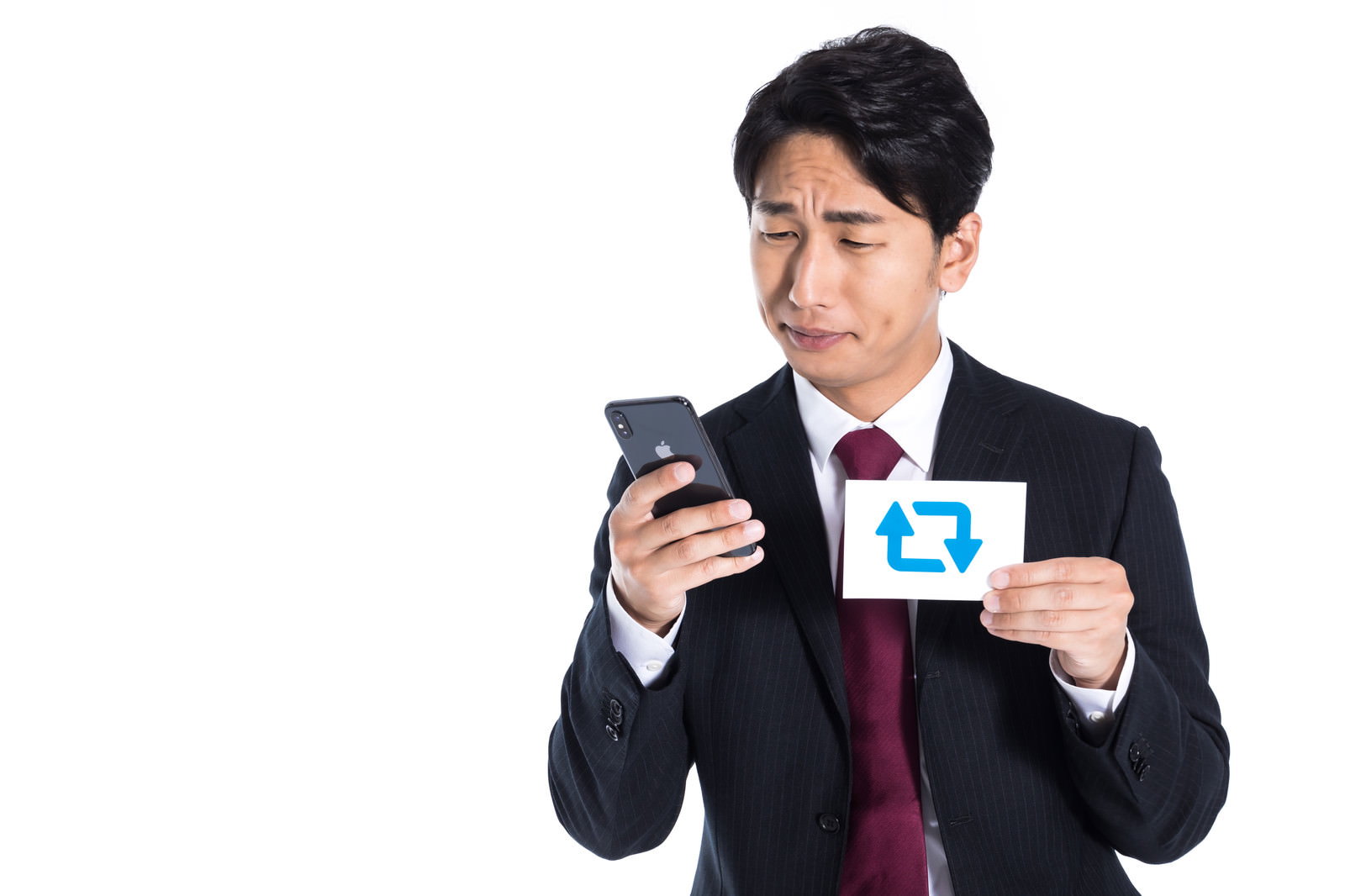 スマートフォンを見つめる黒いスーツ姿の男性［モデル：大川竜弥］