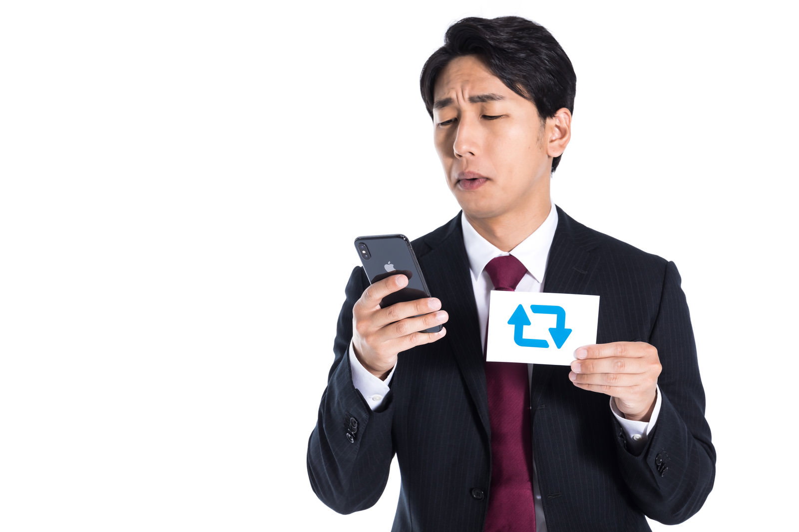 スマートフォンを持ちながら悲しい表情を浮かべるスーツ姿の男性［モデル：大川竜弥］