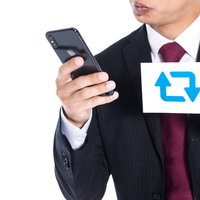 1RTの相場を調べるスーツ姿の男性のスマートフォン操作の写真