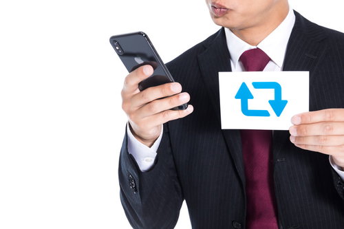 1RTの相場を調べるスーツ姿の男性のスマートフォン操作