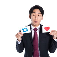 RTと「いいね」で迷うスーツ姿の会社員の写真