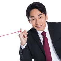 運命の赤い糸を見せびらかす黒いスーツの男性の写真