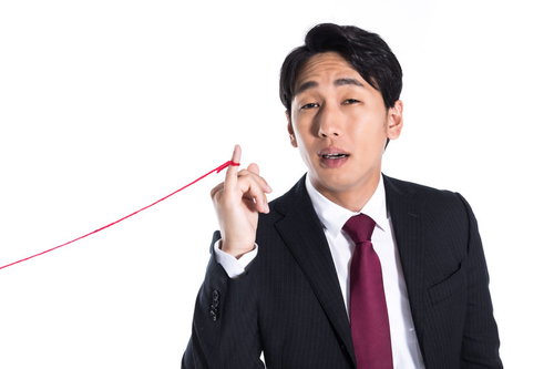 赤い糸を持つモテ男の困惑した表情とスーツ姿