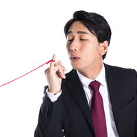 赤い糸を必死に手繰り寄せるサラリーマンの写真
