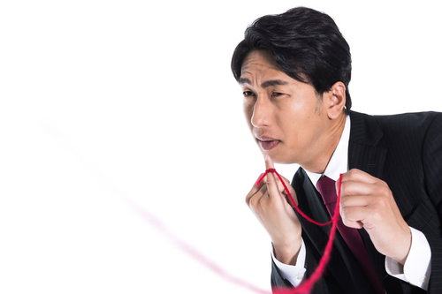 運命の赤い糸をたぐり寄せるスーツ姿の独身男性