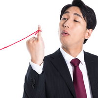 赤い糸を手にした上から目線の男性会社員のポートレートの写真