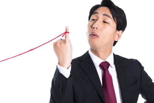 赤い糸を手にした上から目線の男性会社員のポートレート