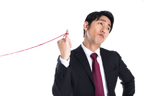 片想いの赤い糸に気付かない会社員男性の横顔