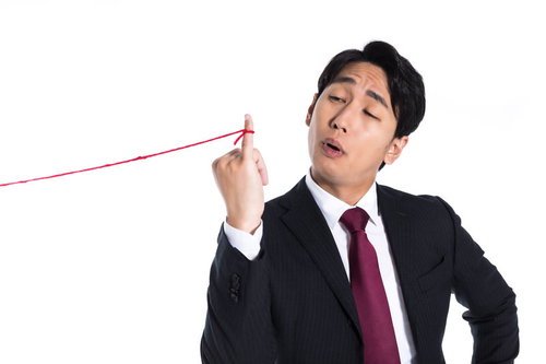 小指に赤い糸が結ばれている事に気が付く会社員