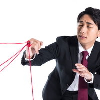 複数の赤い糸に絡まる突然のモテ期到来に戸惑う男性の写真