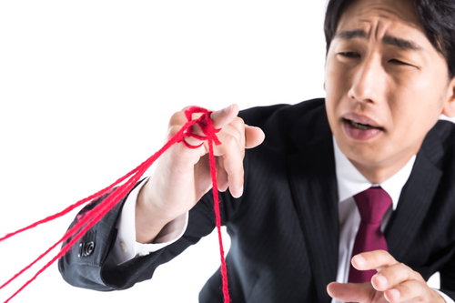 たくさんの運命の赤い糸に困惑するスーツ姿の男性