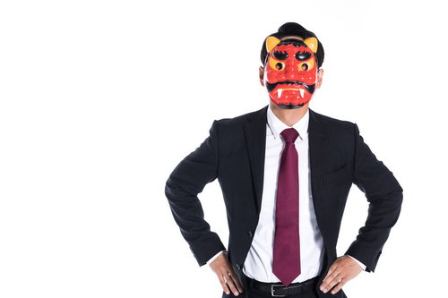 スーツ姿で鬼のお面をかぶり腰に手を当てた男性