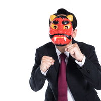 激怒する鬼の面の会社員がファイティングポーズ、黒スーツで戦闘態勢の写真