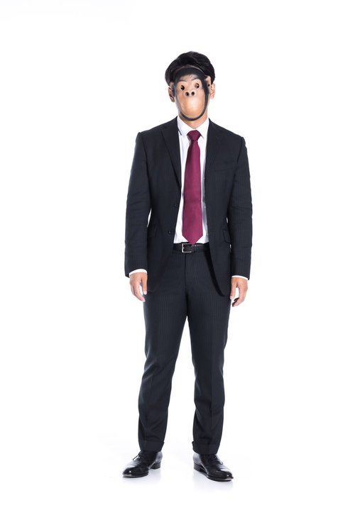 呆然と立ち尽くす仮面姿の会社員、匿名性を表現したビジネス