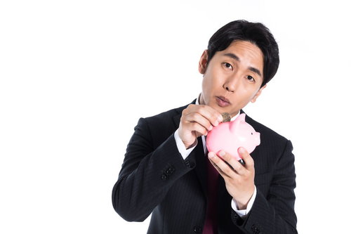 趣味は500円貯金です。ピンクの貯金箱を抱えるスーツ姿の男性