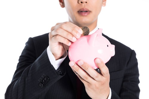 お小遣いの残りを貯金箱に入れるスーツ姿の男性