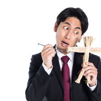 五寸釘と藁人形を持つスーツ姿の復讐代行人の写真
