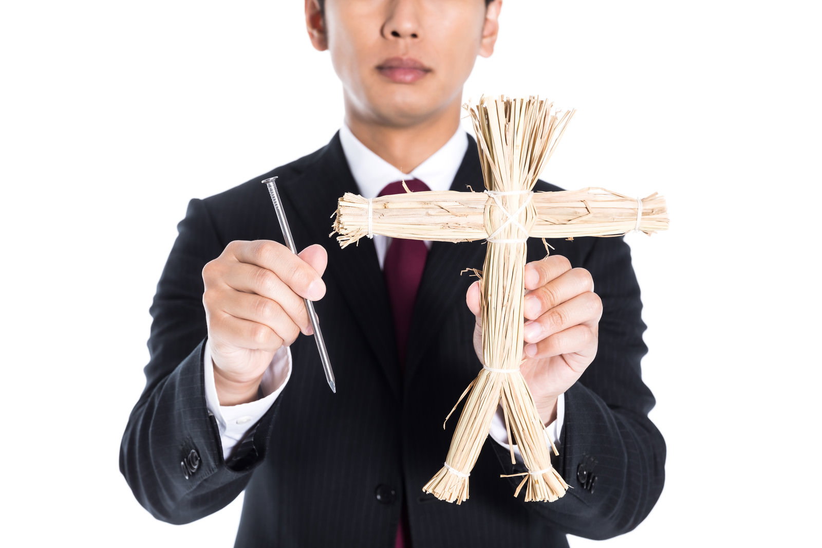 黒いスーツを着た男性が五寸釘と藁人形を両手に持っている［モデル：大川竜弥］