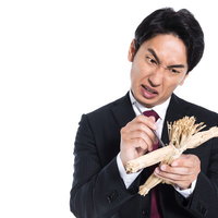 黒いスーツのサラリーマンが藁人形に五寸釘を刺すの写真