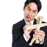 藁人形の使い方をレクチャーするスーツ姿の呪師の写真