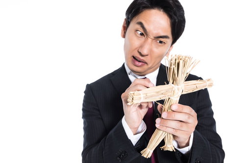 藁人形の使い方をレクチャーするスーツ姿の呪師