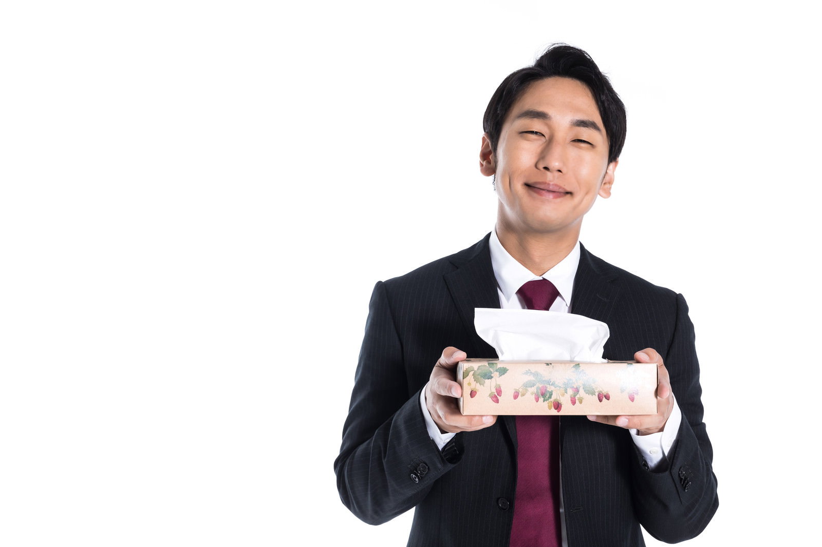 黒いスーツを着た男性が白い箱ティッシュを両手で持ち満足げな表情［モデル：大川竜弥］