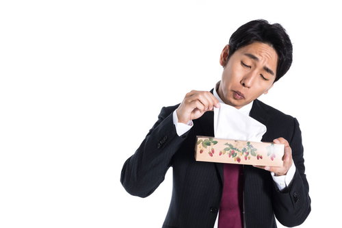 残り僅かな箱ティッシュの中身を確認する会社員男性