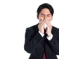 鼻炎で仕事にならない会社員がティッシュで鼻をかむの写真