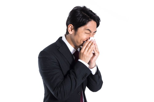 ティッシュで鼻をかむスーツ姿の男性、花粉症や風邪の症状