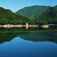 青空と山々が映り込む川治ダムの湖面の写真