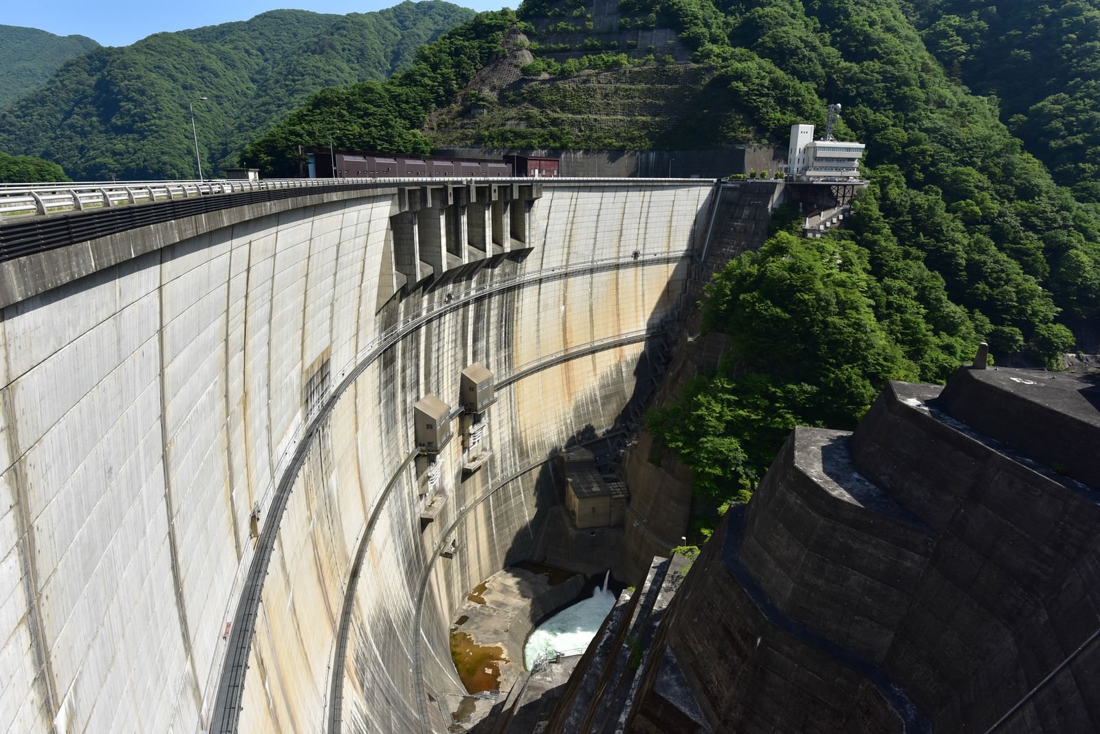 緑の山々に囲まれた白いアーチ型コンクリートダムの川治ダム