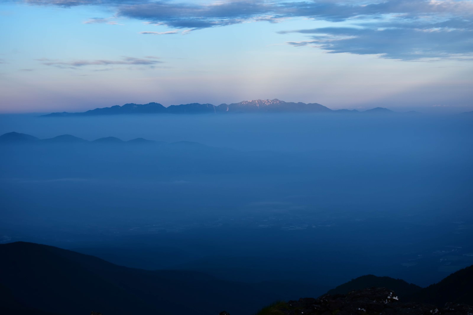 夜明け前の連峰と霞む山並み、眼下に広がる街