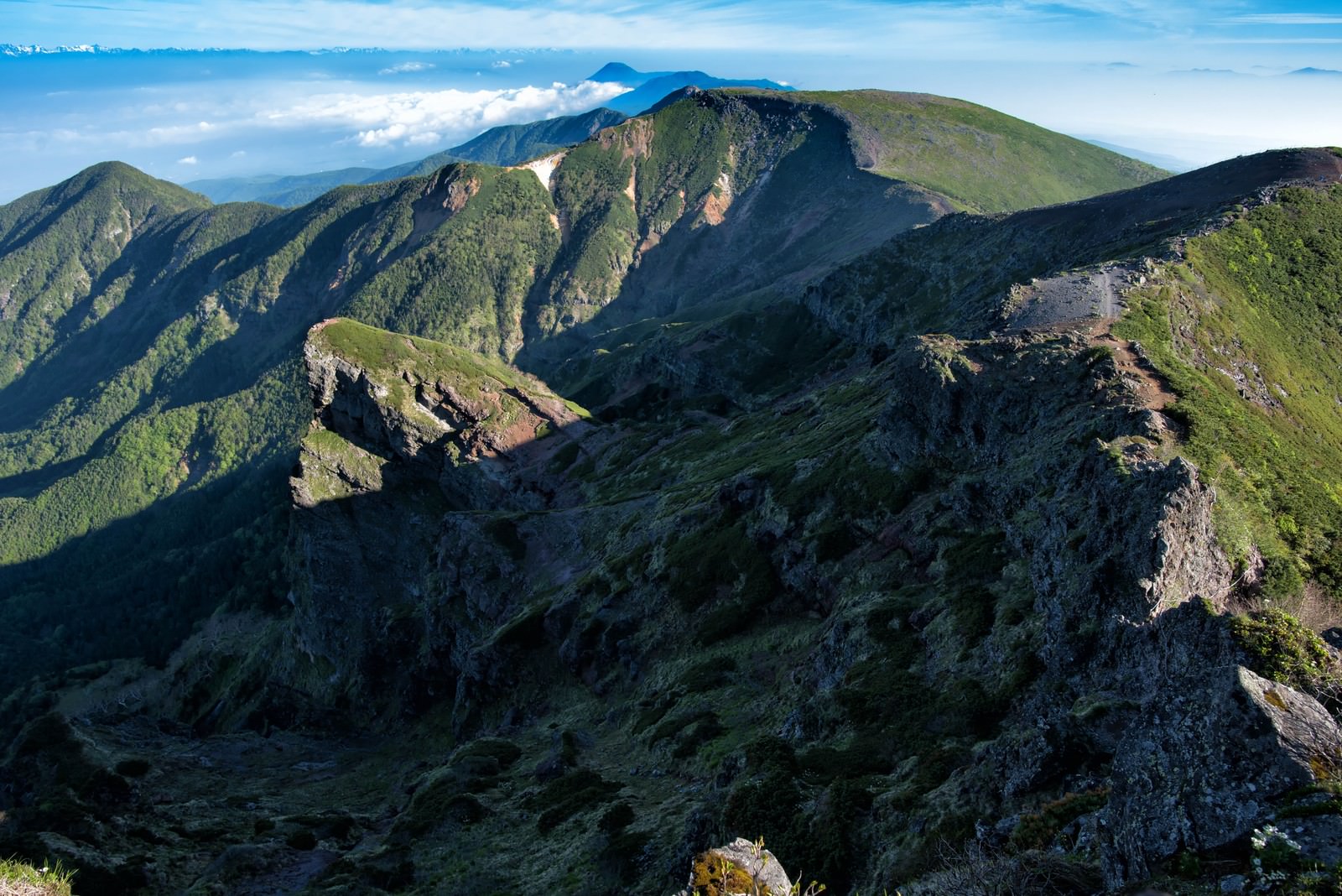 横岳山頂から続く険しい岩場の登山道と山並みの風景