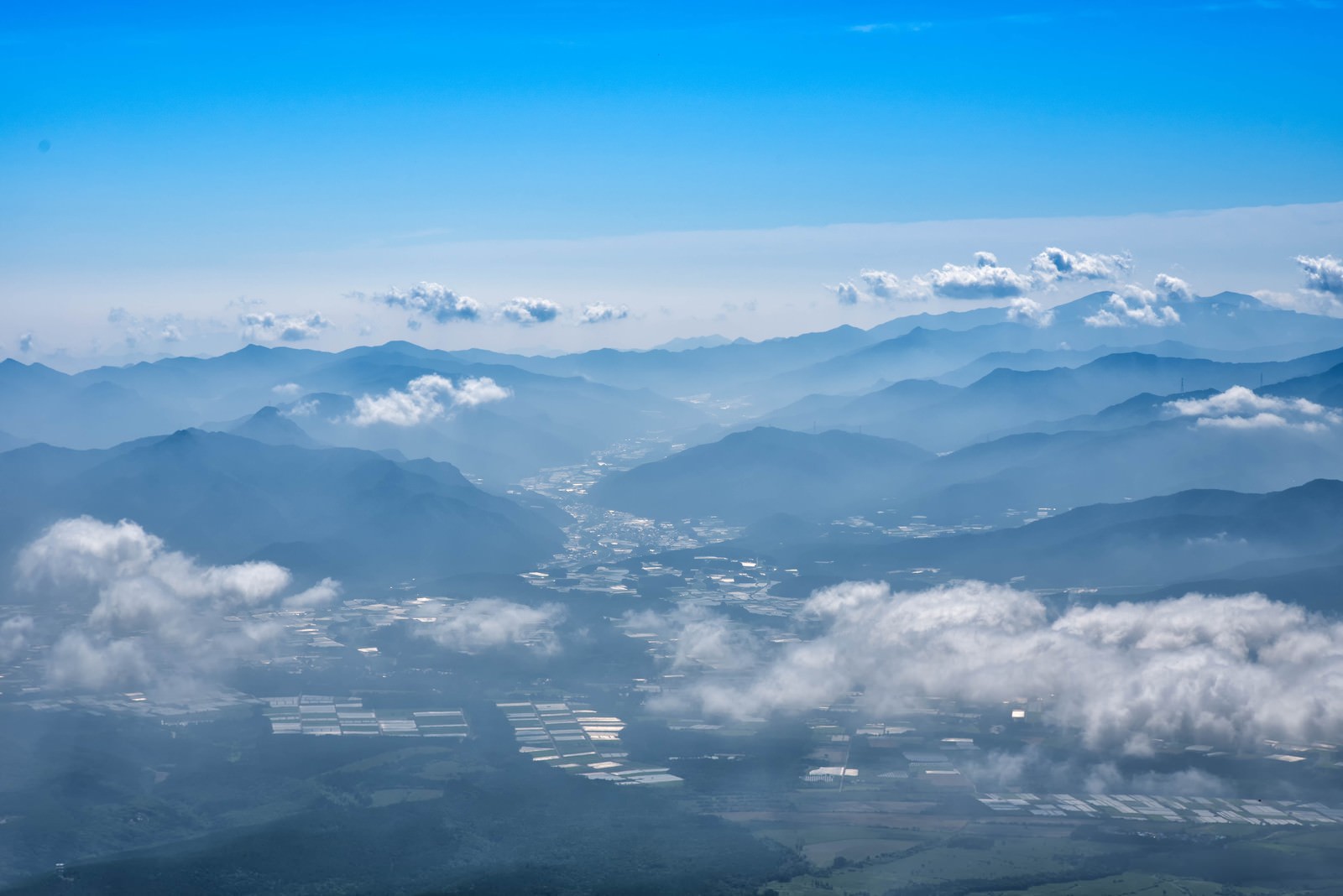 清里高原の緑豊かな水田と霞がかった山並み、雲海が見える田園風景