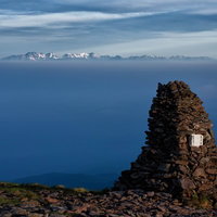 硫黄岳のケルンと遥かに望む北アルプスの山並みの写真