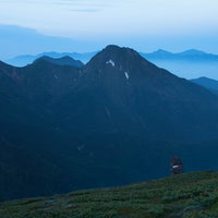 硫黄岳のケルンと霞がかる阿弥陀岳、南アルプス連峰の写真