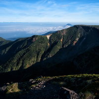 硫黄岳のえぐられた爆裂火口と夜明けの山並みの写真