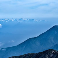 霞がかかった蓼科山と後立山連峰の山岳風景の写真