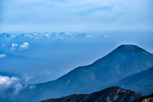 霞がかかった蓼科山と後立山連峰の山岳風景