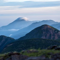 霞がかり雲のかかる蓼科山と重なり合う山並みの写真